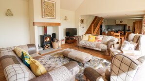 A cozy living room with a fireplace, sofas, and a television. - The Orchard (Knighton)