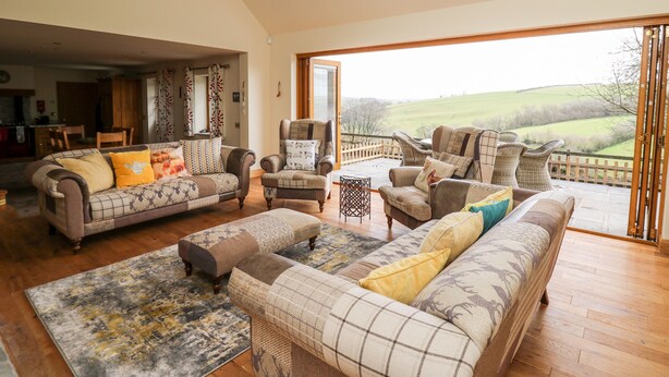 A spacious living room with a large window offering a view of the countryside. - The Orchard (Knighton)