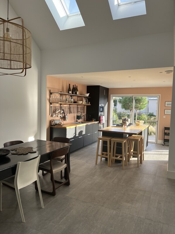 A modern kitchen with a central island, built-in appliances, and a dining area with a table and chairs.