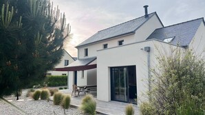 Ett modernt hus med ett sluttande tak, en täckt uteplats och en grusuppfart.