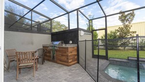 Une terrasse extérieure avec un barbecue, des sièges et une piscine.