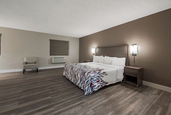 A bedroom with a bed, bedside tables, a chair, and a window with blinds.