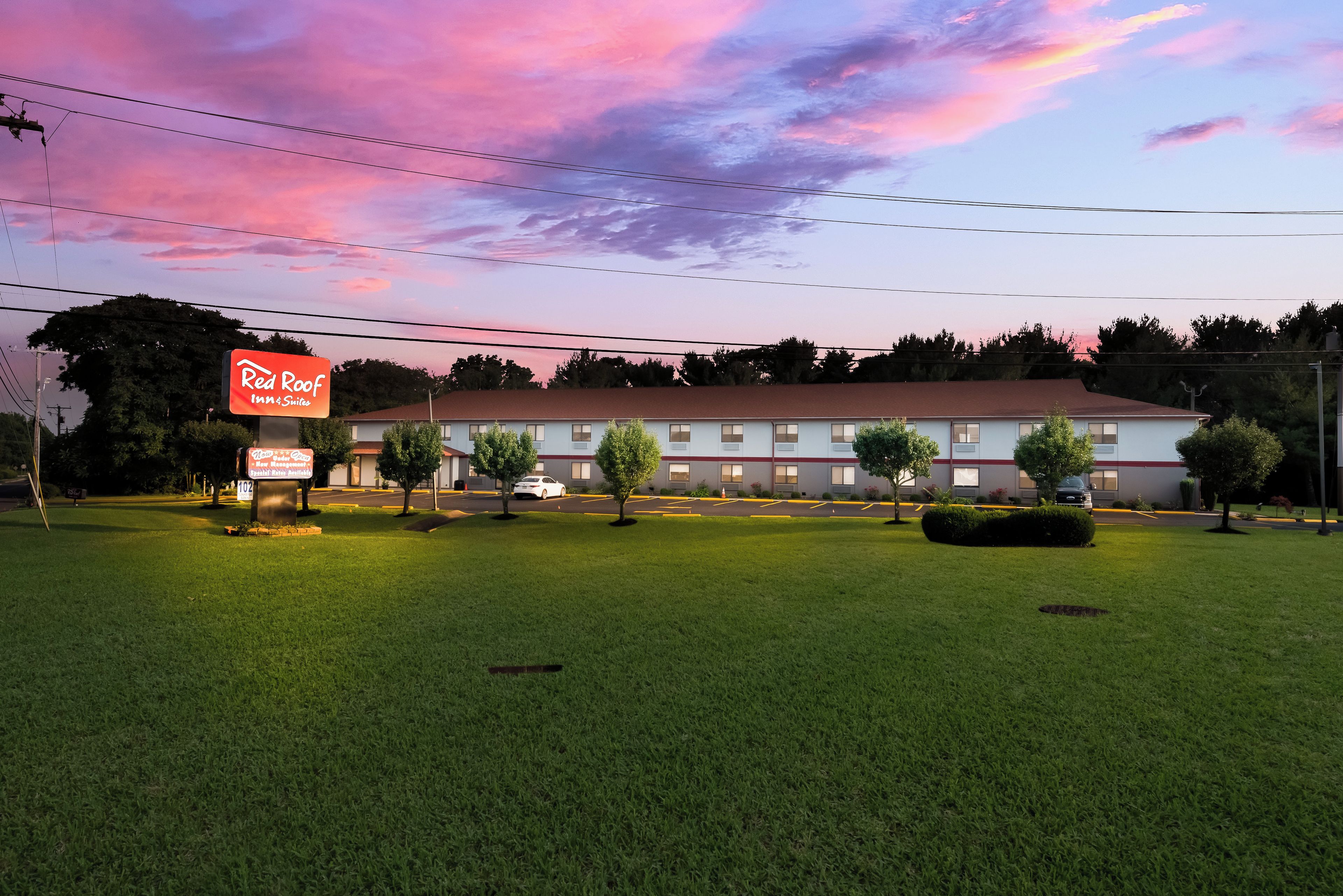 A Red Roof Inn & Suites with a well-maintained lawn and a clear view of the building.