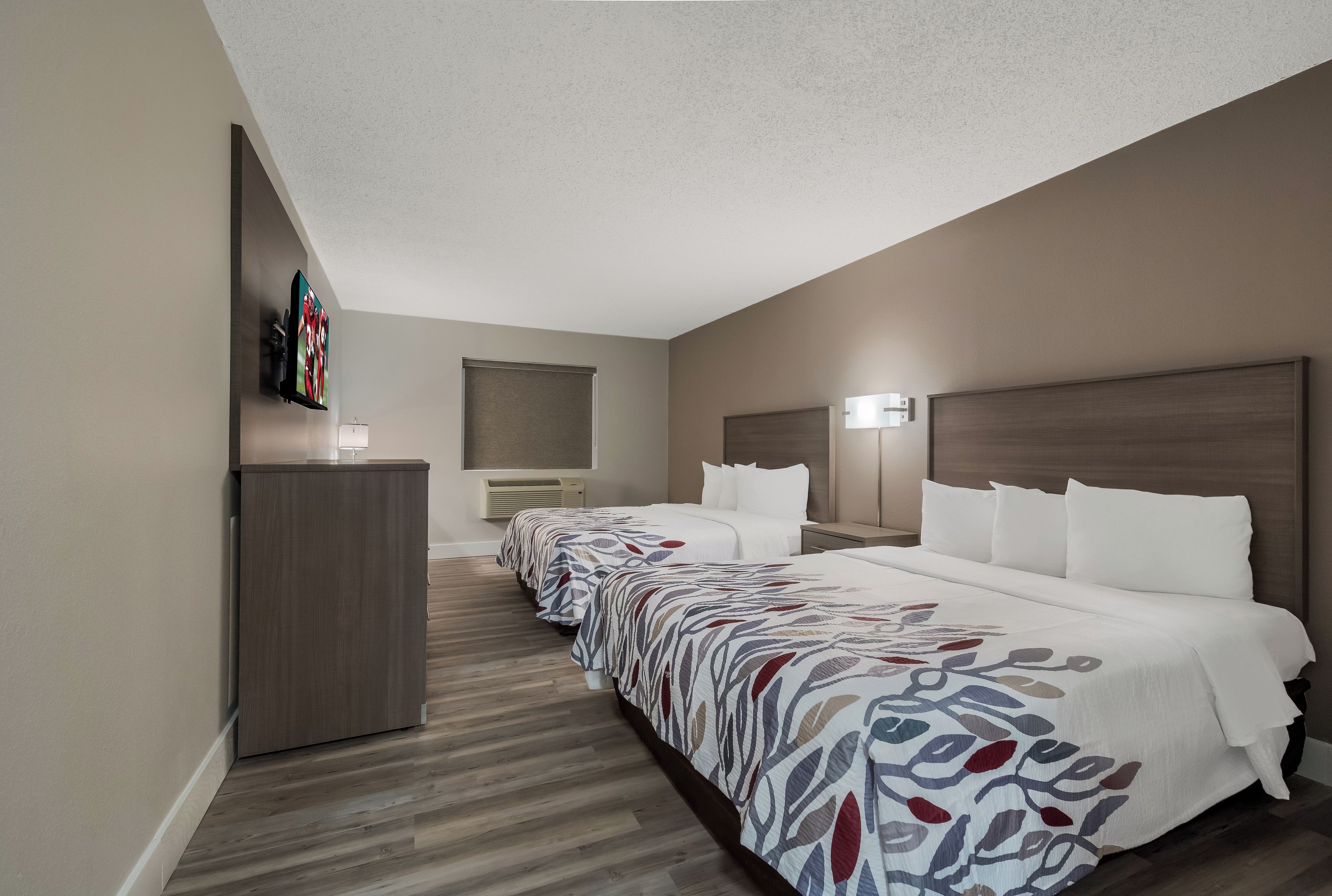A hotel room with a large bed, a bedside table, a lamp, a TV, and a wardrobe.