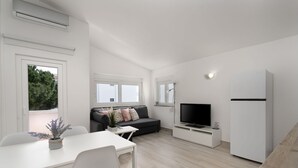 A modern, minimalist living room with a sofa, TV, and white cabinetry. - Bright Albufeira - 5min to the beach by LovelyStay (Albufeira)