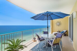 Enjoy the ocean view from this balcony with a table, chairs, and umbrella.