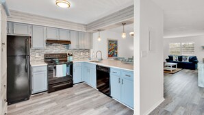 A modern kitchen with light blue cabinets, a black refrigerator, and a built-in oven. - ⭐Sandprints A12-350yds 2 Beach-2BR ⭐ (Miramar Beach)