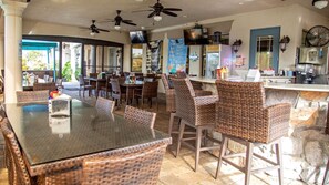 Enjoy meals in this spacious dining area with wicker chairs and a glass table, featuring a kitchen and bar counter.