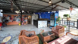 Un área de estar al aire libre con muebles de mimbre, una mesa y un refrigerador de Pepsi.