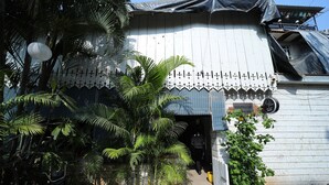 Un edificio con fachada blanca, un acceso cubierto y un letrero que indica una cafetería.
