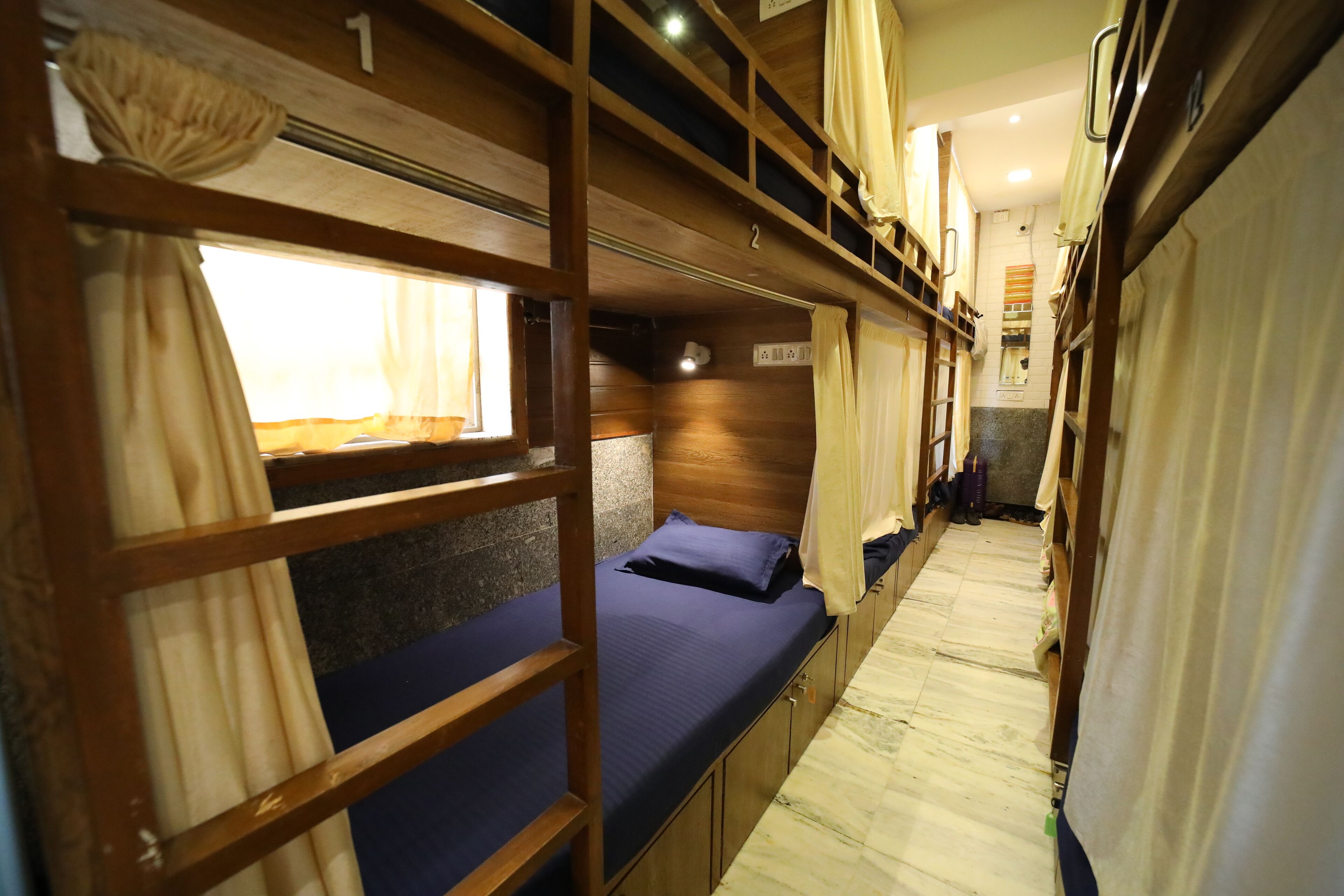 A train compartment with bunk beds, wooden walls, and a narrow corridor.