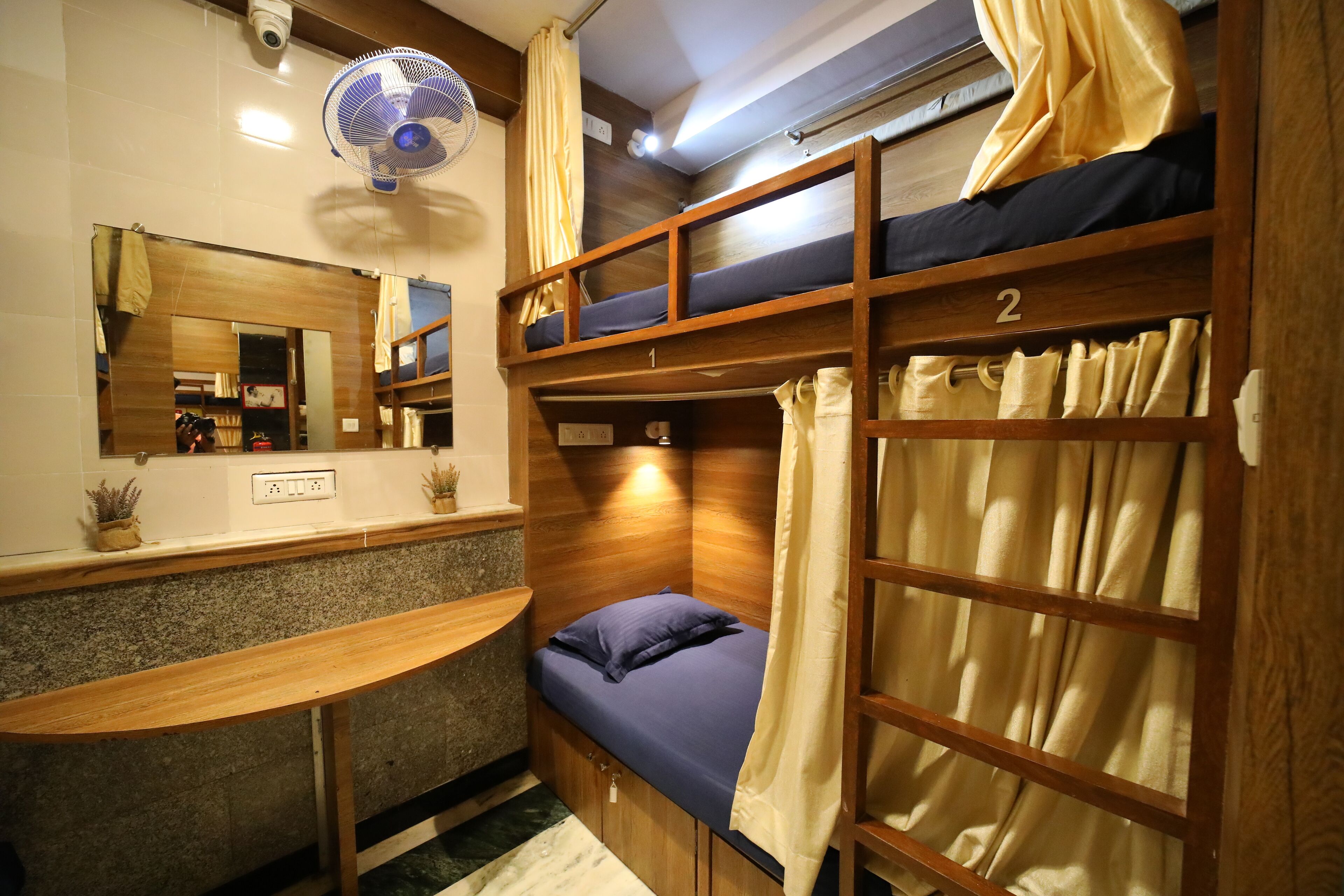 A bunk bed room with a desk and a mirror.