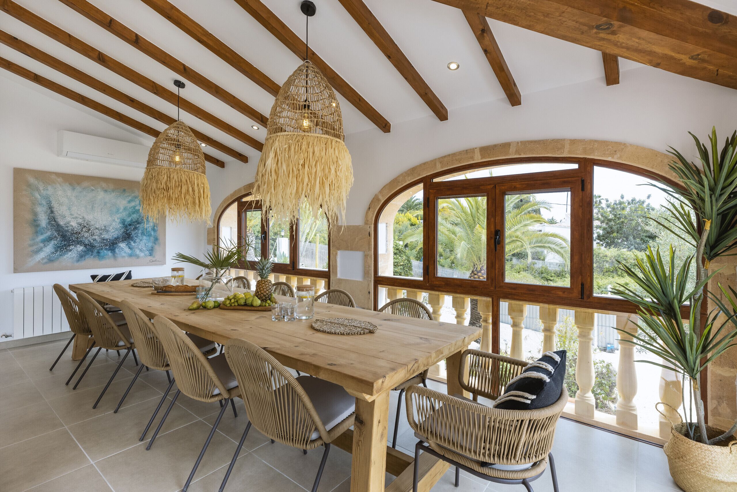 Un coin repas avec une table en bois, des chaises en osier et un luminaire suspendu.