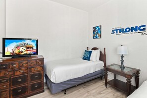 A bedroom with a bed, a dresser, a television, a lamp, and a motivational poster on the wall.