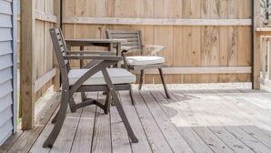 Eine Terrasse mit Holzdeck, zwei Stühlen und einem Tisch.