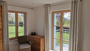 Un dormitorio con cama, escritorio, silla y ventana con cortinas.