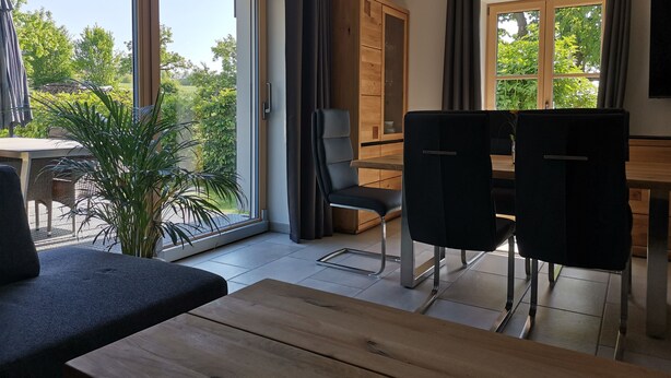 Un comedor moderno con una mesa de madera, sillas negras y un ventanal con vistas a zonas verdes.