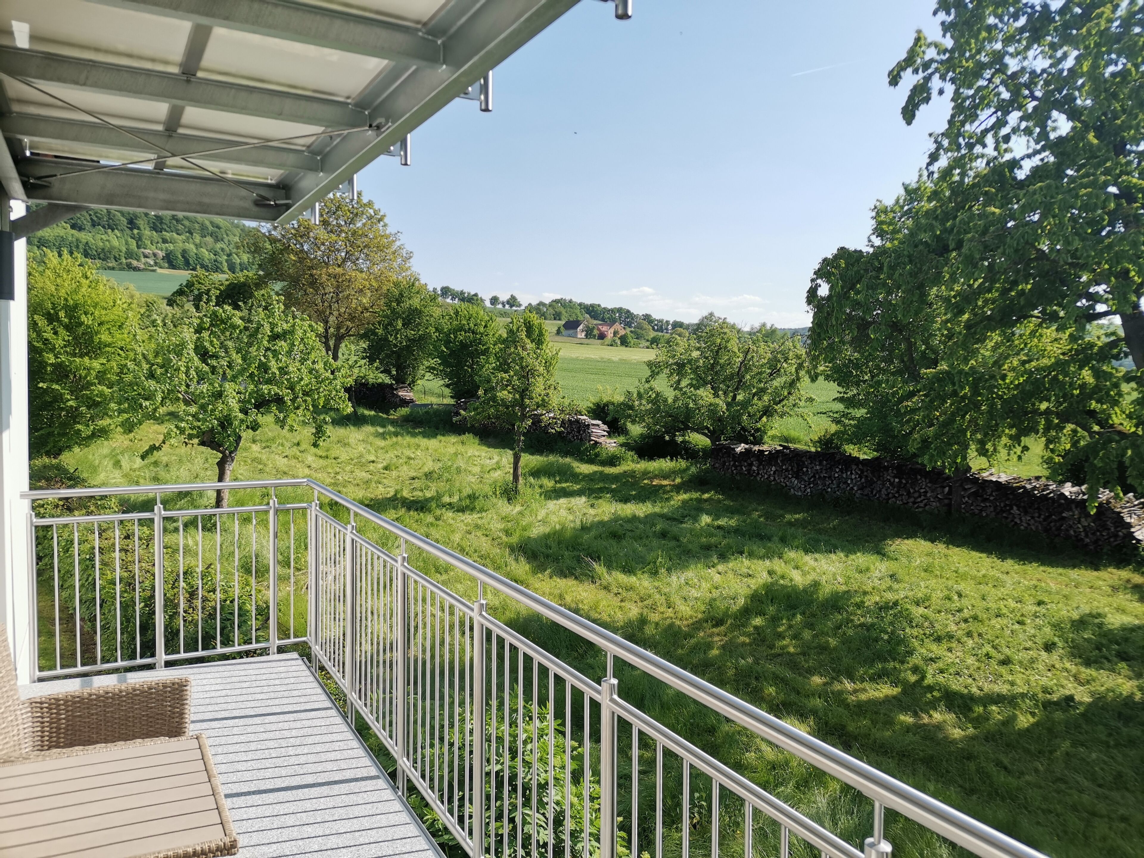 Ein Balkon mit Blick auf ein grünes Feld und Bäume.