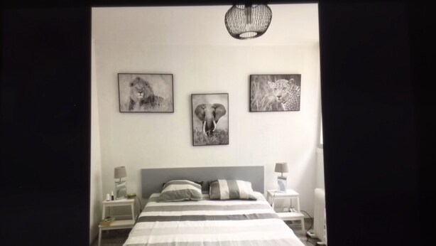 Ein Schlafzimmer mit einem Bett, zwei Nachttischen und drei gerahmten Bildern an der Wand.