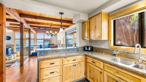 Cocina amplia con armarios de madera, encimeras de granito y un ventanal con vistas al exterior.