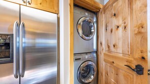 Una cocina con electrodomésticos de acero inoxidable, armarios de madera y lavadora y secadora integradas.