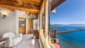 Una habitación con techo de madera, un ventanal grande con vista a un cuerpo de agua, un sofá blanco y una pequeña mesa.