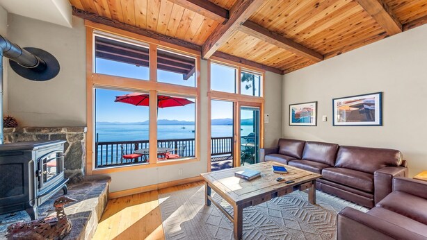 Una sala de estar acogedora con chimenea de piedra, un sofá de cuero marrón, una mesa de centro de madera y ventanas amplias con vistas panorámicas.