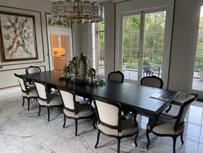 Uma sala de jantar com uma mesa comprida, seis cadeiras e um candelabro.