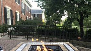 A square fire pit with a tiled border, surrounded by a brick pathway and a metal fence. - 13,000 sq. ft. 6BR Estate on 5 acres Swim Spa, Hot Tub, Pool Table, Game Room (Muncie)