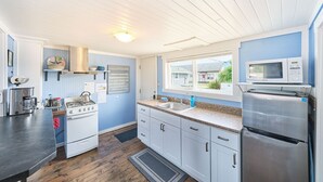 A compact kitchen with a stove, sink, and microwave, featuring a window with a view of the outside.
