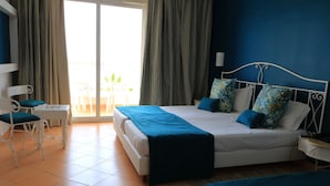 Un dormitorio con cama, mesitas de noche, una silla y vistas al exterior.