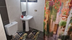 Un baño con inodoro, lavamanos y cortina de ducha.