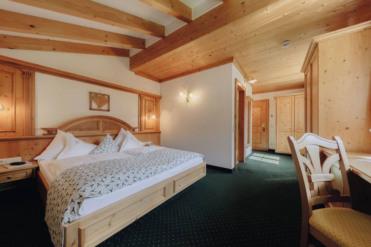 A wooden-framed bedroom with a bed, a chair, and a desk.