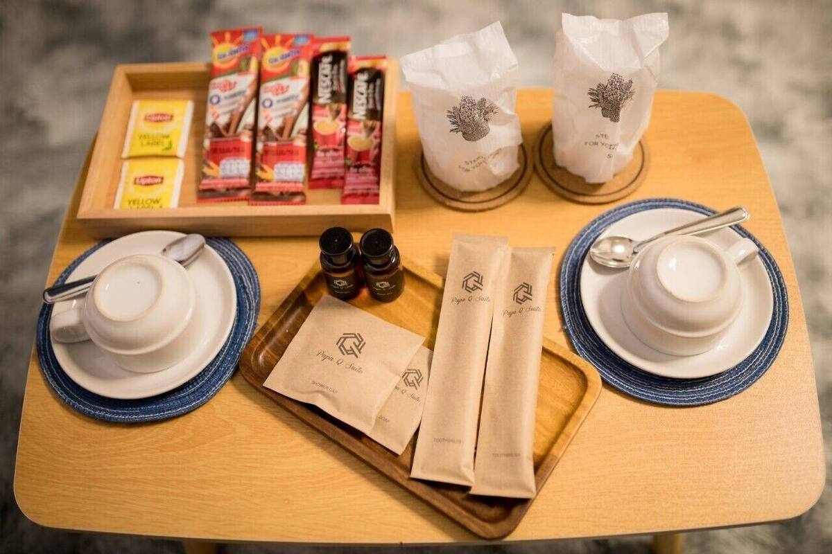A breakfast tray with coffee, tea, and packaged snacks on a wooden table.