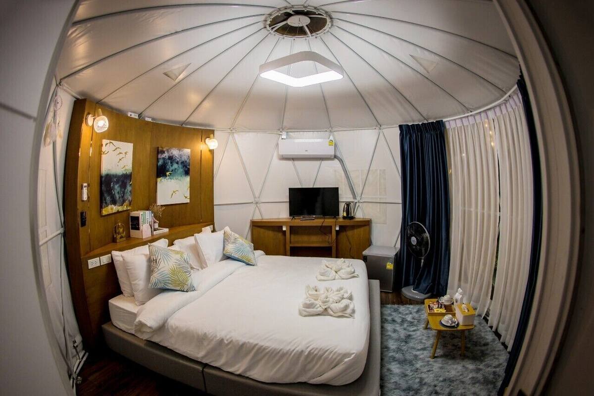 A compact, well-lit room with a bed, bedside table, and a television.