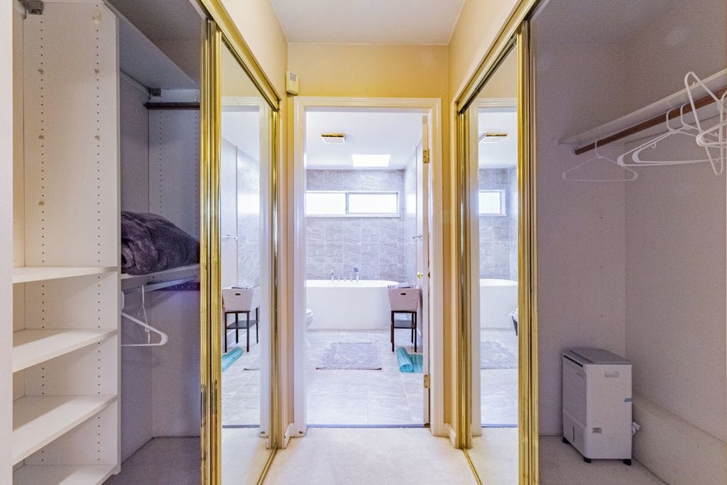 A narrow hallway leading to a bathroom with a bathtub, a sink, and a chair.