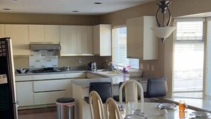 Una cocina moderna con armarios blancos, un comedor con una mesa redonda y sillas, y un amplio ventanal que proporciona luz natural.