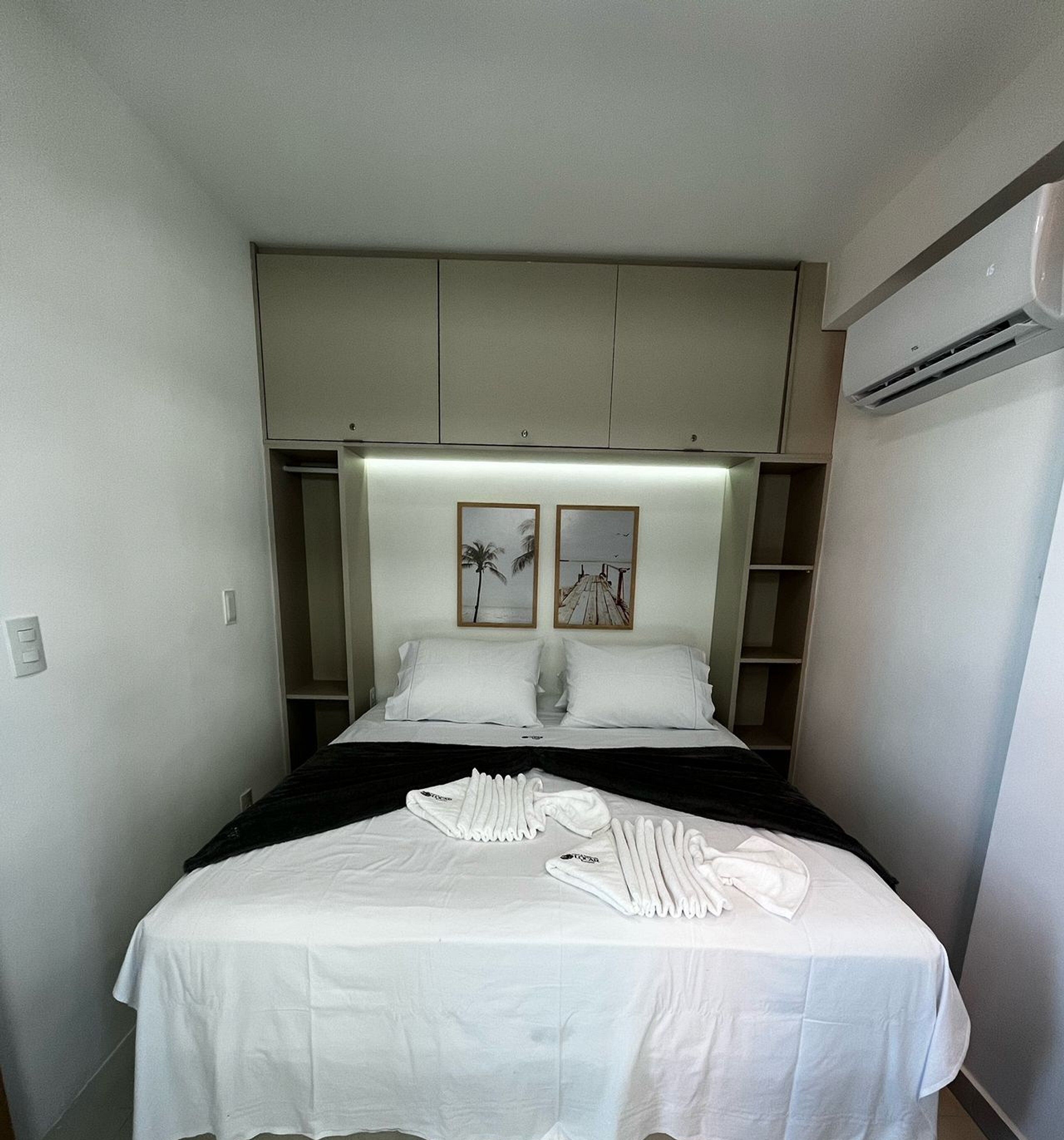 Quarto de hotel com uma cama, mesa de cabeceira, guarda-roupa e ar condicionado.