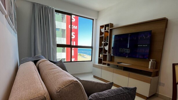 Ein modernes Wohnzimmer mit großem Fenster, Flachbildfernseher und einer eingebauten Holzregal.