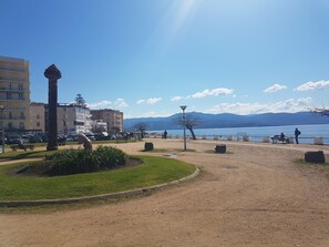 A park with a palm tree, benches, and a view of a lake and mountains.