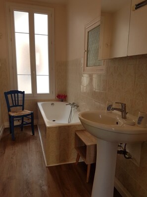 A bathroom with a bathtub, a sink, and a window.
