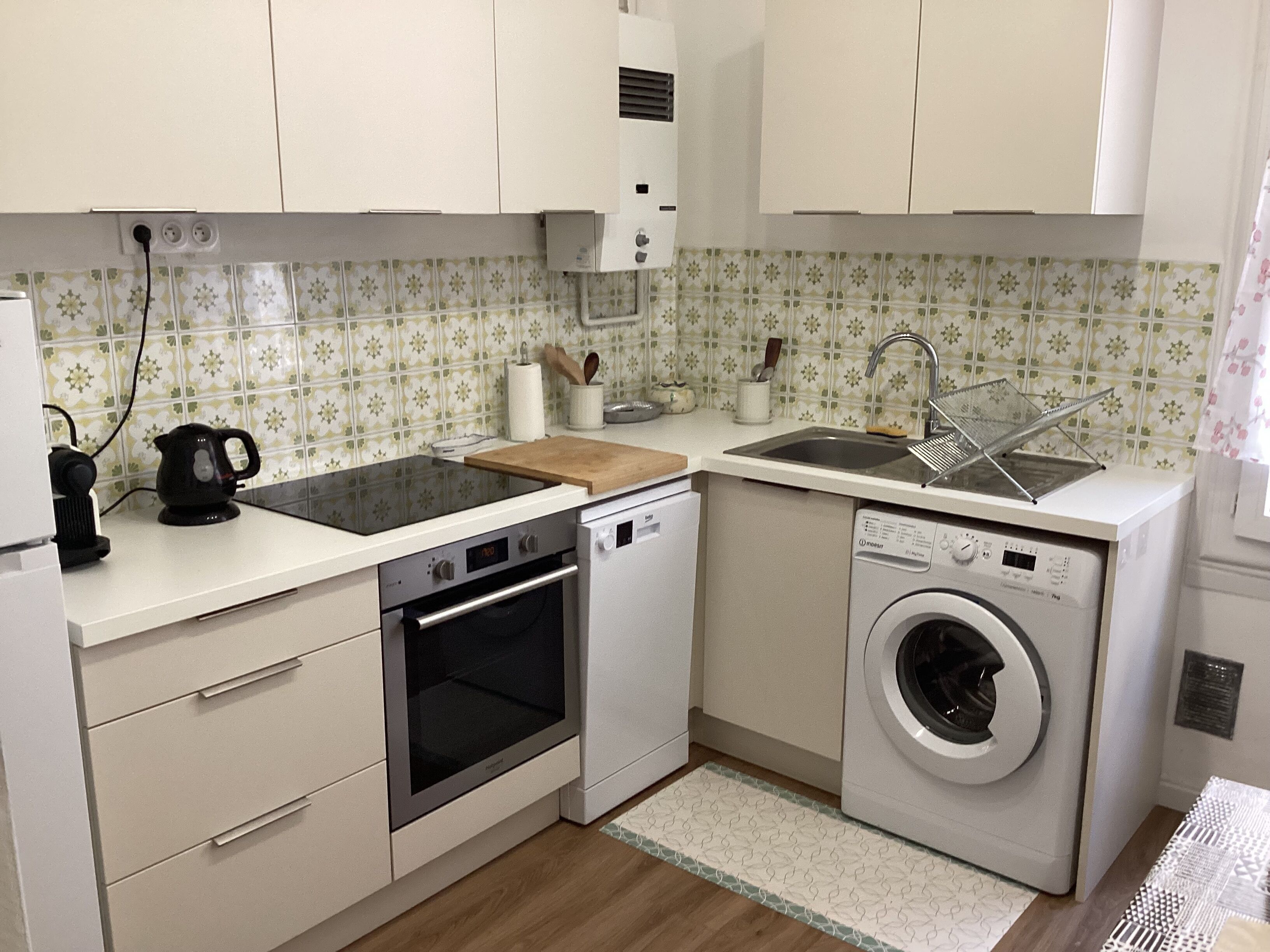 A compact kitchen with a dishwasher, oven, and washing machine.