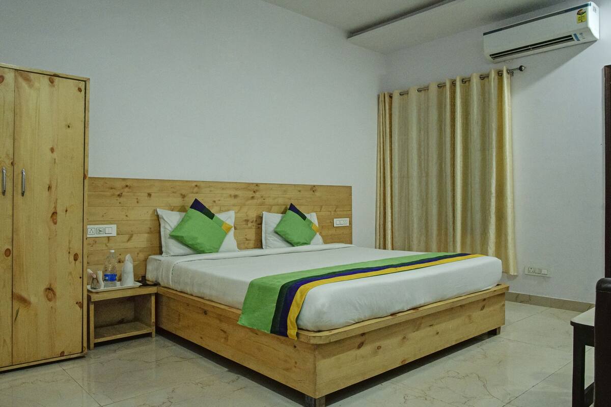 A wooden bed with a headboard, a wooden wardrobe, a bedside table, and a curtain.