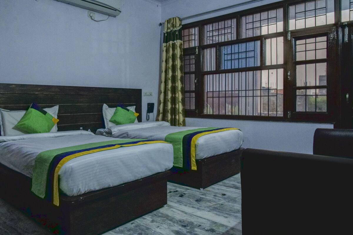 A room with two beds, a wooden headboard, a window with bars, and a chair.