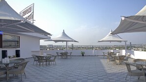 A rooftop terrace with checkered flooring, wicker furniture, and white umbrellas. - Treebo The King Mohali (Mohali)