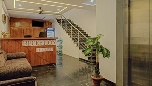 A reception area with a wooden desk labeled "RECEPTION THE KING," a staircase, and a potted plant. - Treebo The King Mohali (Mohali)