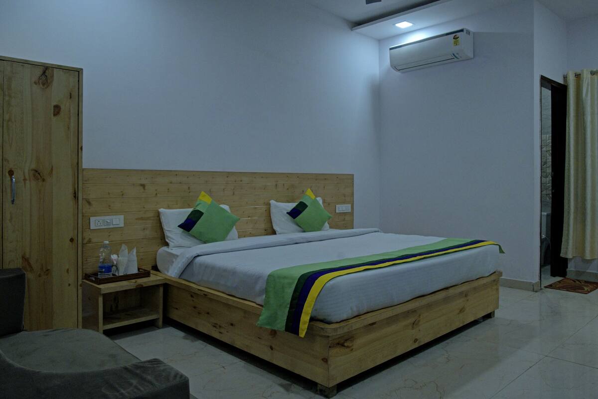 A wooden bed with a headboard, a bedside table, a water bottle, and a pillow.