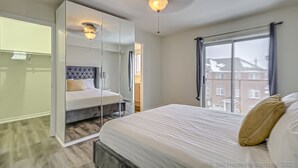A modern bedroom with a bed, a large mirror, and a ceiling fan. - Urban Retreat A Modern 5BR Townhouse (Toronto)