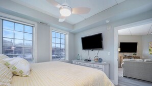 A bedroom with a bed, a dresser, a television, and a ceiling fan. - 2 Bedroom River Front Condo (Manistee)