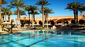 Ein Pool mit Palmen und Liegestühlen, umgeben von einem Geb äude mit Bögen.
